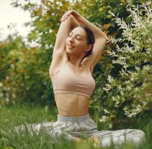 Pretty lady training in a summer park. Brunette doing yoga. Girl in a sportsuit.